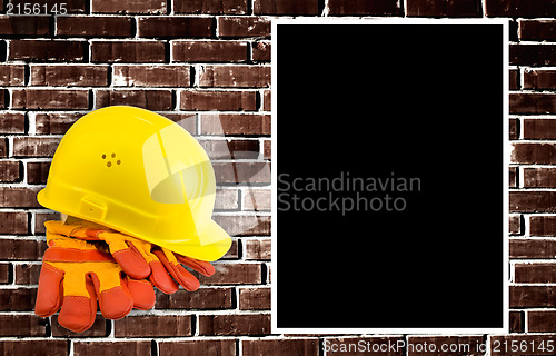 Image of Yellow hard hat and protective gloves with grunge wall backgroun