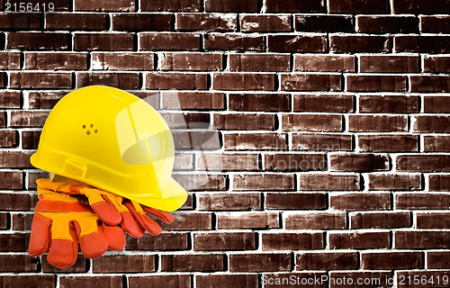 Image of Yellow hard hat and protective gloves with grunge wall backgroun