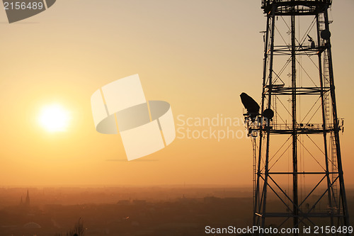 Image of Communication tower at sunset with cityscape