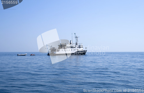 Image of Ship and several boats going into the sea.