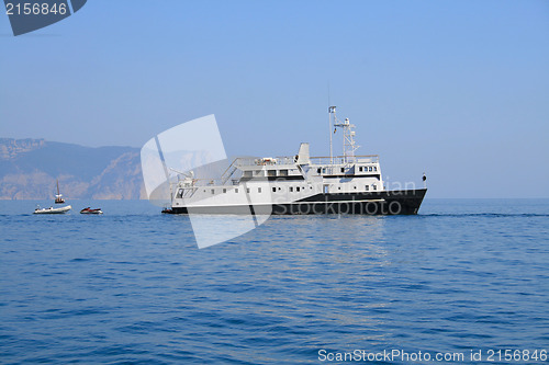 Image of Ship and several boats going into the sea.