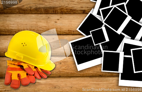 Image of Yellow hard hat and protective gloves with grunge wall backgroun