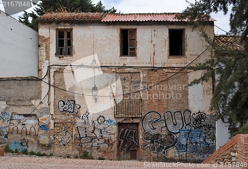 Image of Facade of a deserted house with bricked-up windows and graffiti