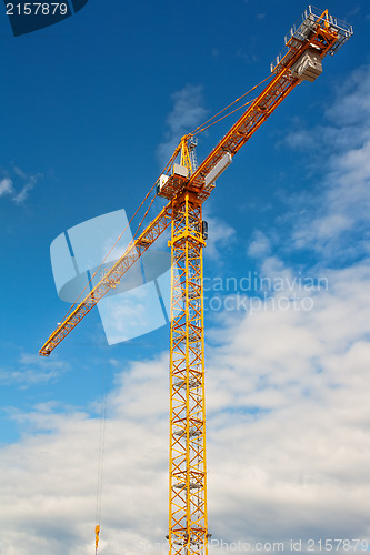 Image of Tall white tower crane against bright blue sky.