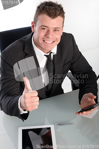 Image of Enthusiastic young businessman showing thumb up