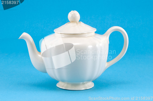 Image of retro ceramic white teapot dish on blue background 