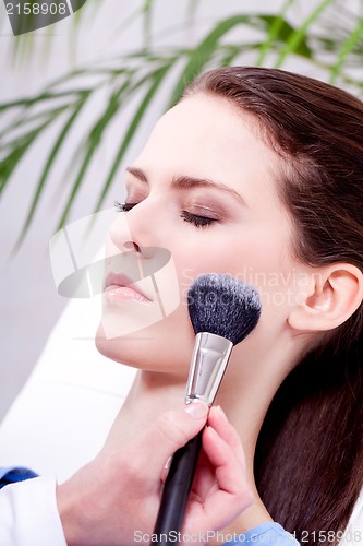 Image of apllying powder make up on face portrait