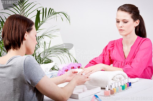 Image of young brunette woman get manicure in salon