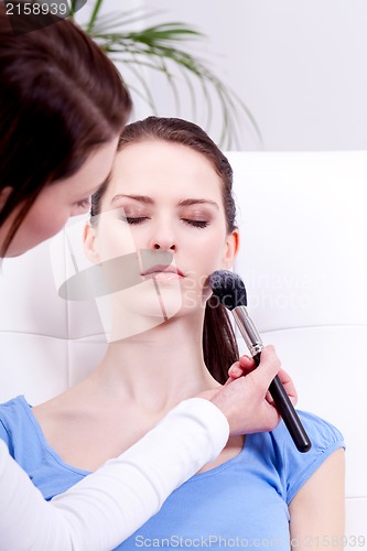 Image of apllying powder make up on face portrait