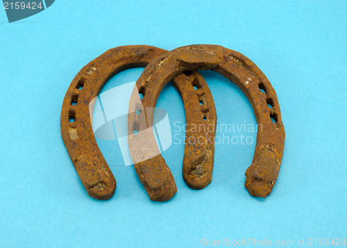 Image of retro rusty pair of horseshoes on blue background 