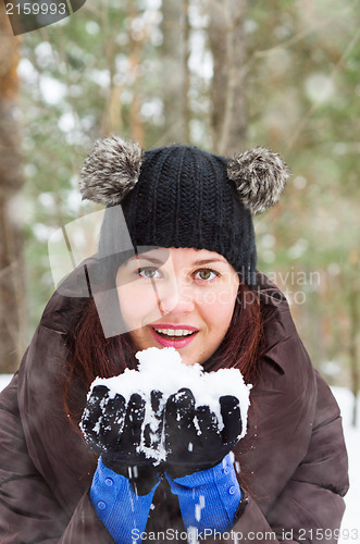 Image of Cute young woman playing with snow  outdoors