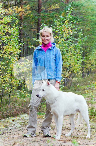 Image of The woman with a dog walk in an autumn wood