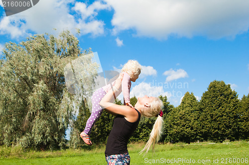 Image of Mother raising her little daughter up high 