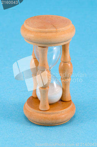 Image of wooden sand glass clock stand on blue background 