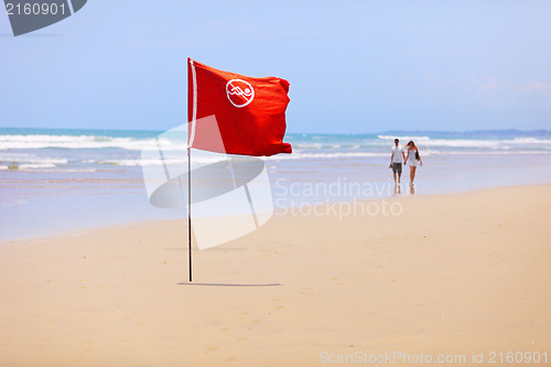 Image of Tropical beach and a red flag. Do not swim!