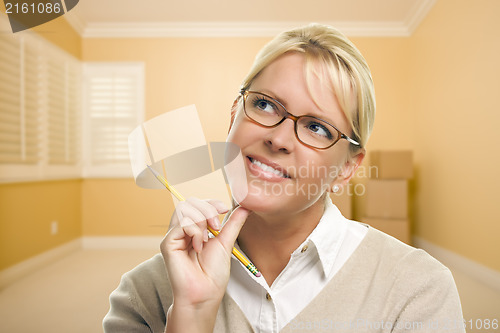 Image of Daydreaming Woman with Pencil in Empty Room and Boxes