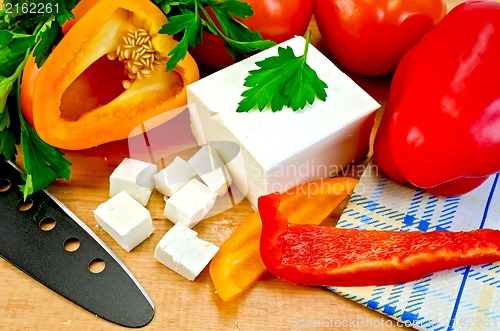 Image of Feta cheese on the board with vegetables and herbs