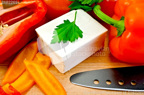 Image of Feta cheese with a knife and vegetables