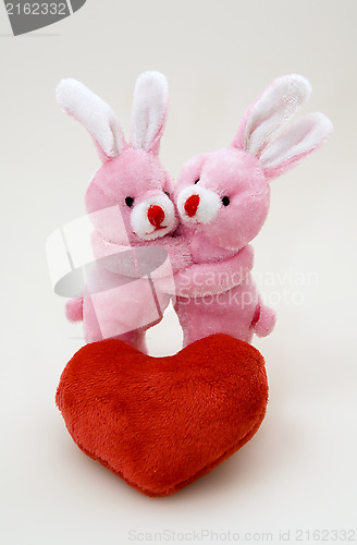 Image of Two bunny hug each other close to the plush heart 