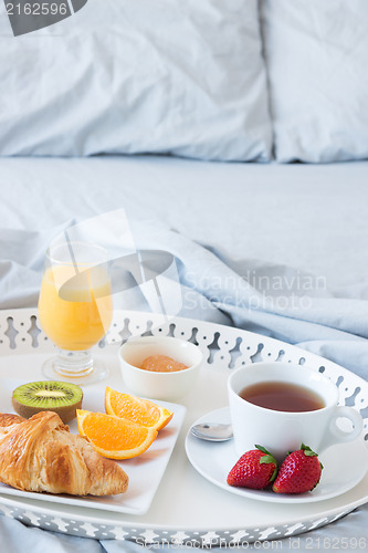 Image of Tray with tasty breakfast on a bed