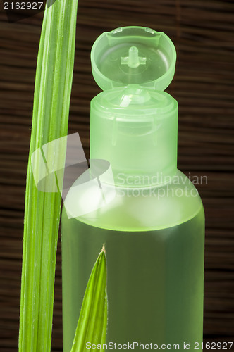 Image of Green cosmetic bottle and leaf