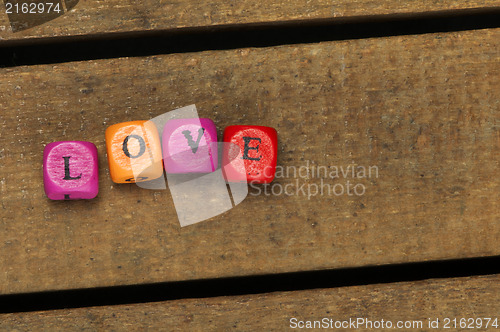 Image of Word love on multicolored wooden cubes on wood