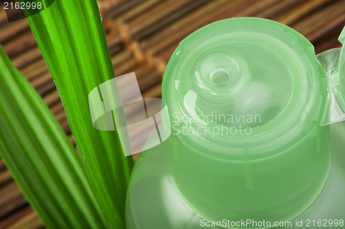 Image of Green cosmetic bottle and leaf