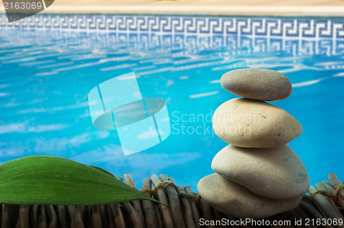 Image of Stacked stones on wooden base for spa and green leaf
