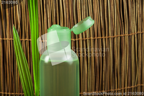 Image of Green cosmetic bottle and leaf