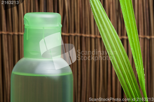 Image of Green cosmetic bottle and leaf