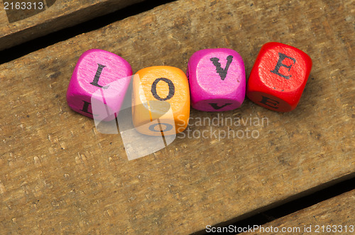 Image of Word love on multicolored wooden cubes on wood