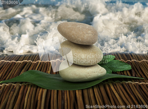 Image of Stacked stones on wooden base for spa and green leafs