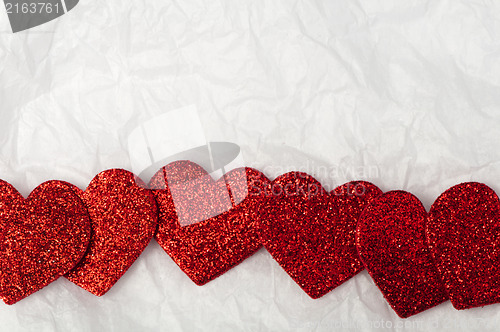 Image of Shiny red hearts on white paper