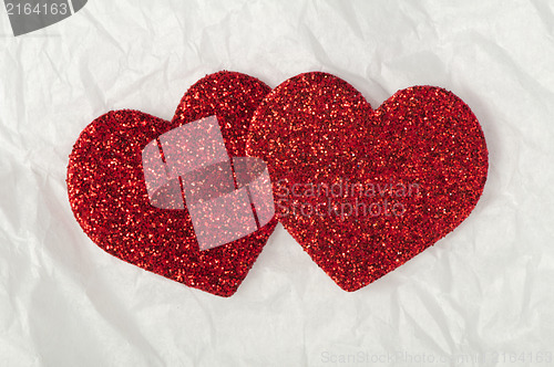 Image of Shiny red hearts on white paper