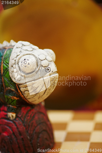 Image of Figurine of chameleon on a chess-board.
