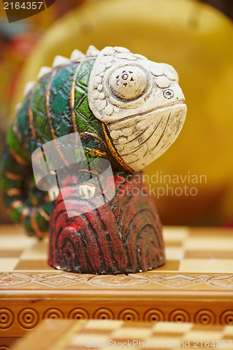 Image of Figurine of chameleon on a chess-board.