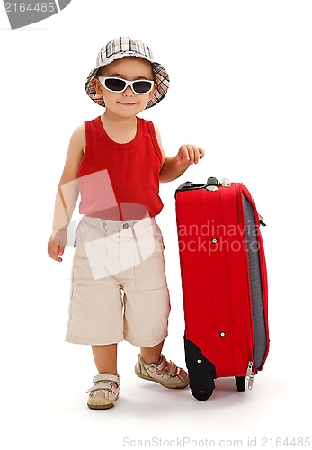 Image of Little boy standing near luggage, ready for journey