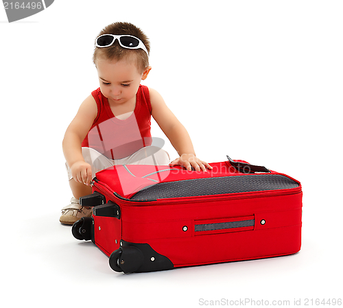 Image of Little boy preparing for trip, zipping suitcase