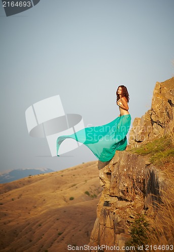 Image of A girl stands on the edge of a cliff.