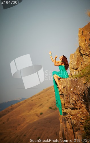 Image of Girl sitting on the edge of a cliff.