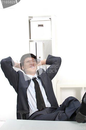 Image of Laughing Asian businessman with his feet up