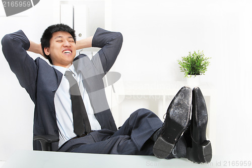 Image of Asian businessman relaxing with his feet up