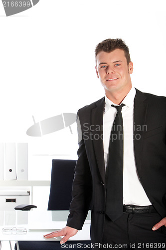 Image of Handsome businessman standing at his desk