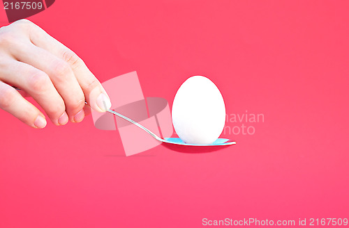 Image of Hand holding an Egg with a Spoon