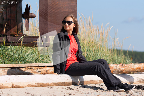 Image of Girl on a deserted beach in the background of an old rusty screw