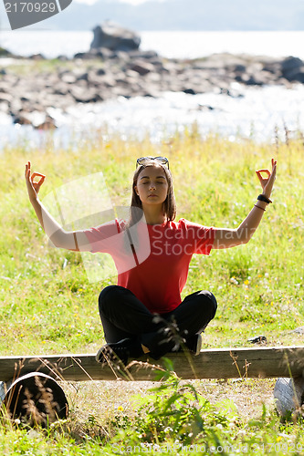 Image of girl in a red dress sitting on a bench in the lotus position