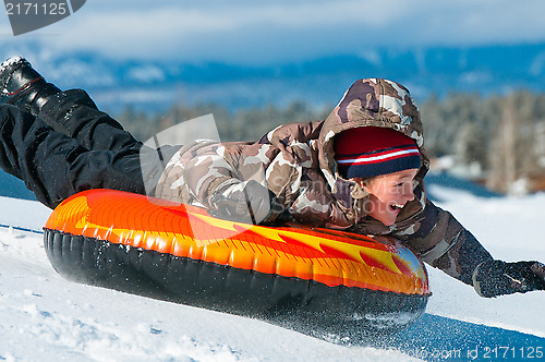 Image of Happy boy riding a tube in snow