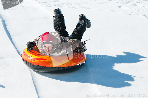 Image of Happy boy sleding on a tube.