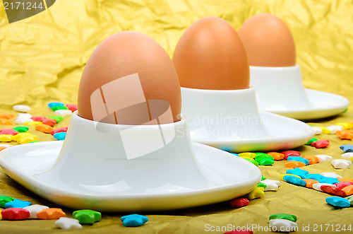 Image of Colorful stars three eggs and egg cups are golden background