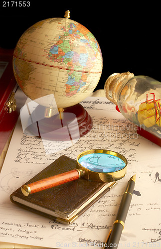 Image of The globe, magnifier with a notebook and the old manuscript. 